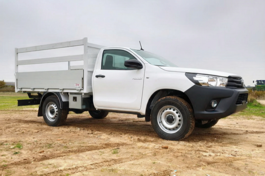 Toyota Hilux blanca carrozada con caja de carga abierta, en una obra