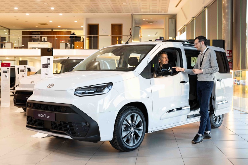 Un comercial de Compostela Móvil atiende a un cliente junto a un Toyota Yaris Cross blanco en el concesionario