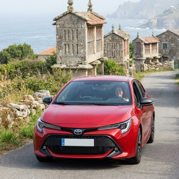 Toyota Yaris rojo aparcado frente a una casa de piedra gallega