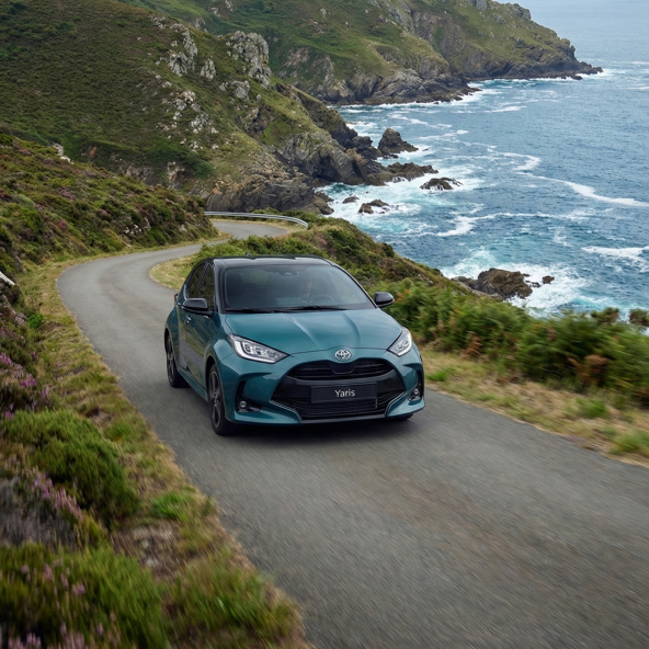 Toyota C-HR azul circulando por una carretera de costa junto a los acantilados